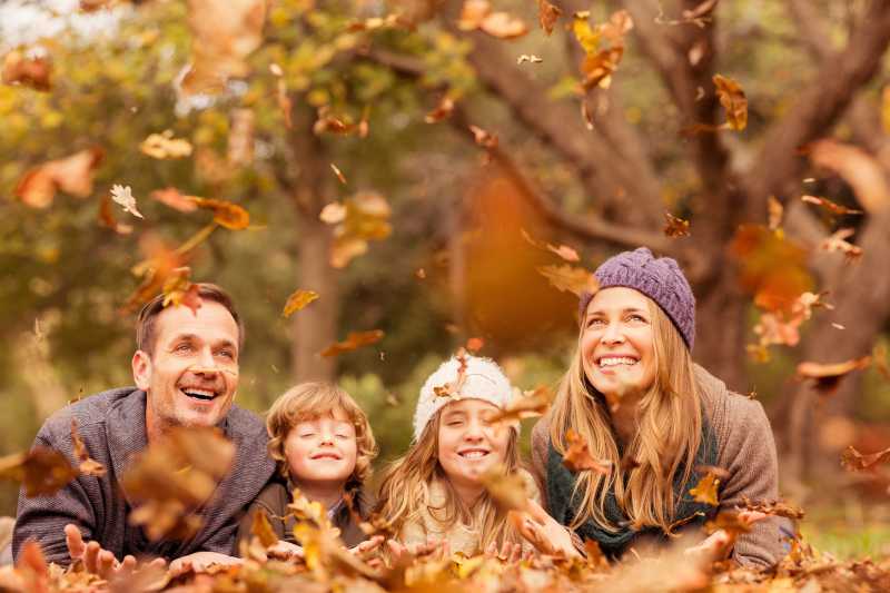微笑的年轻家庭到处扔树叶