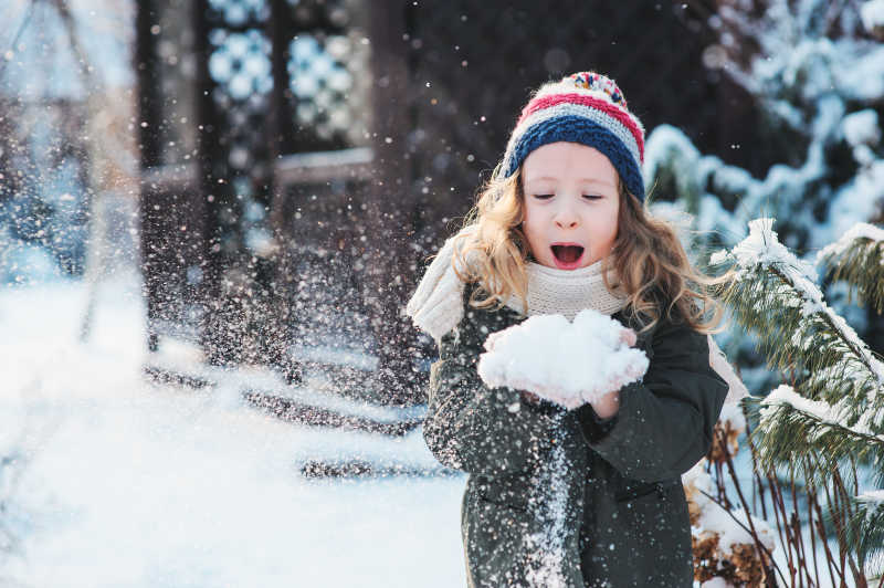 快乐的小女孩在雪地上玩雪
