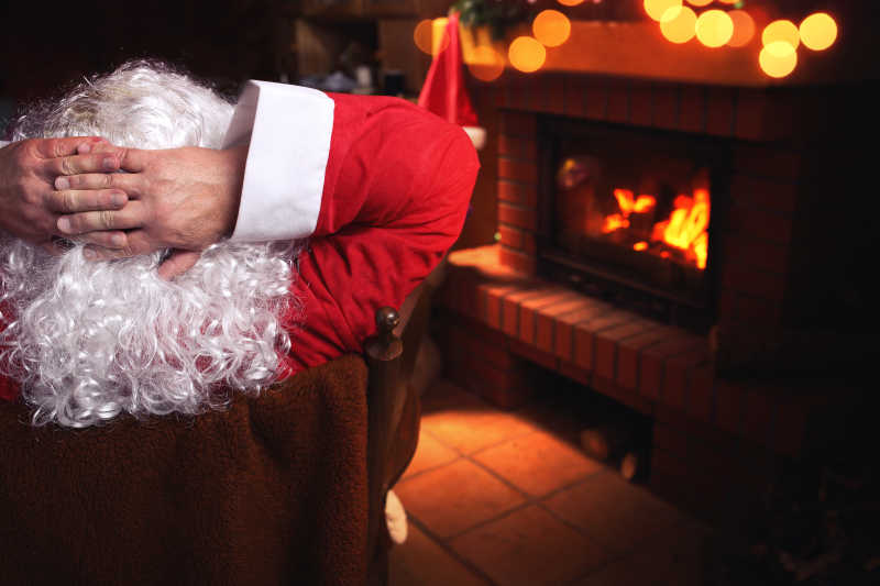 圣诞老人坐在壁炉前的椅子上