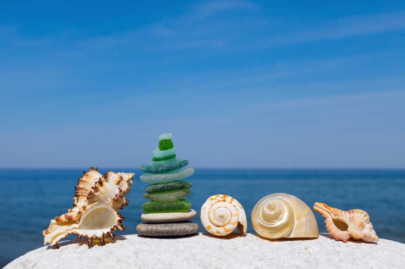 蓝色天空下海边堆叠的石头和贝壳的和谐与平衡的概念