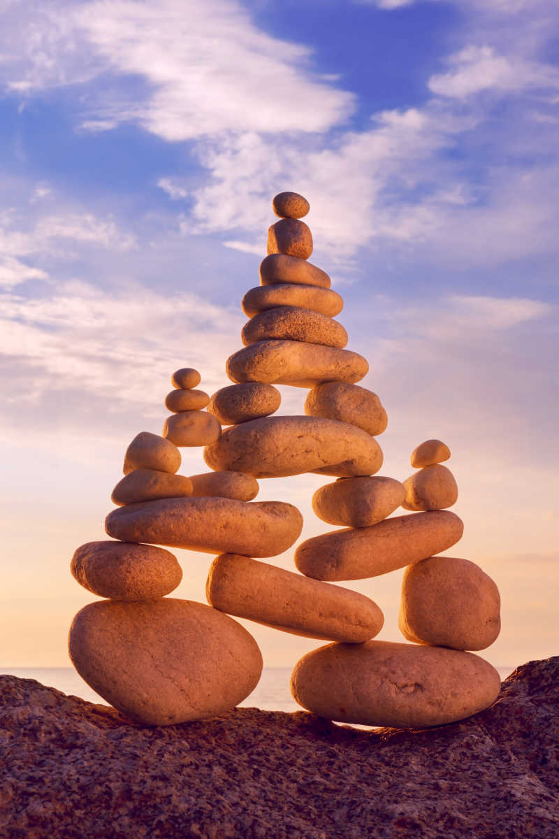 蓝色天空下堆叠的石头的和谐与平衡的概念