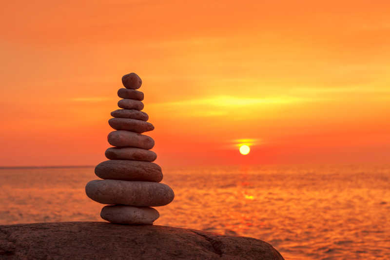 夕阳下海边的石头的和谐与平衡