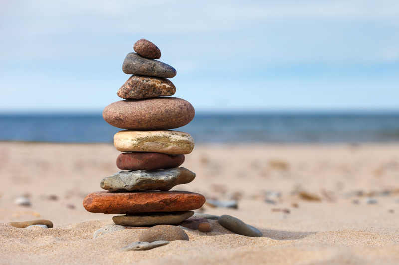 白色沙滩上海边的石头形成的平衡与和谐的概念