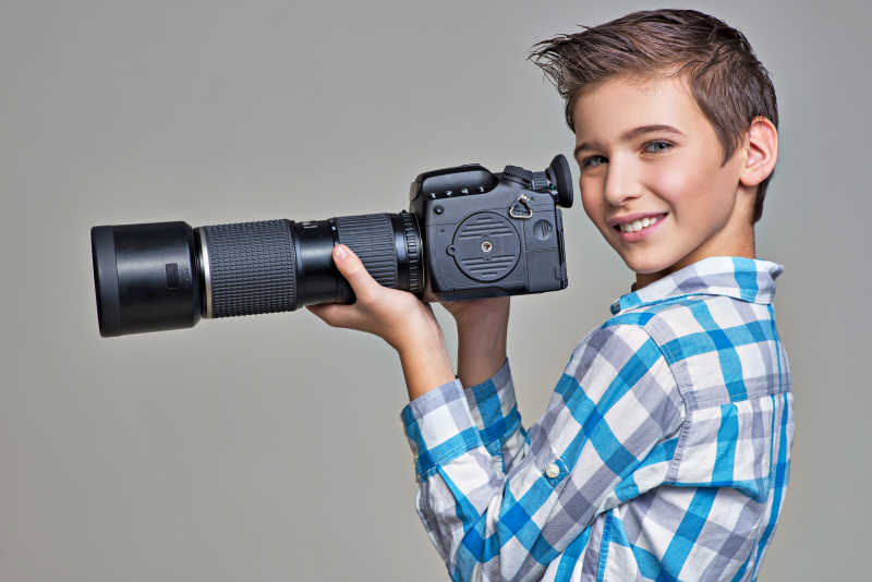 男孩拿着远摄镜头的大相机