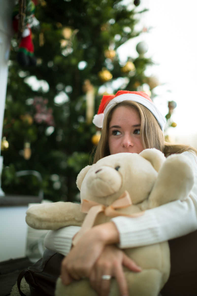 圣诞树下抱着泰迪熊的女孩