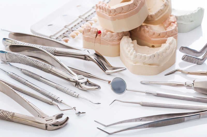 白色背景上的牙科工具与假牙模型