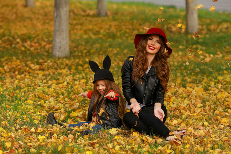 坐在秋季公园草坪上的母女两