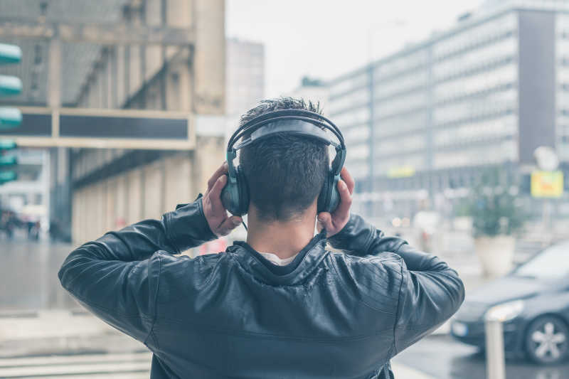 在城市中戴着耳机听音乐的年轻人