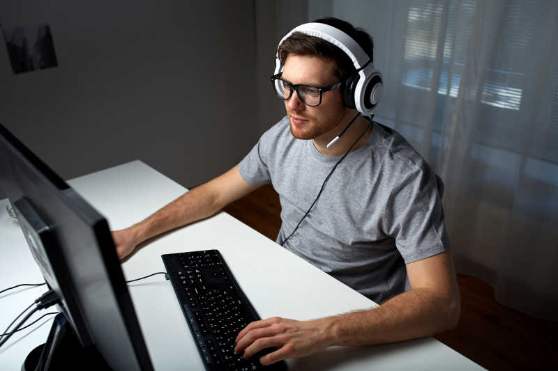 男人戴着耳机玩着电脑游戏