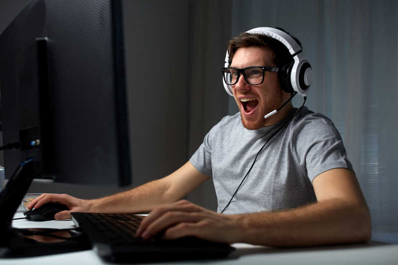 戴着耳机兴奋的玩着电脑的男人