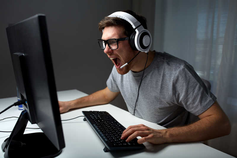 戴耳机的年轻男人在家玩电脑