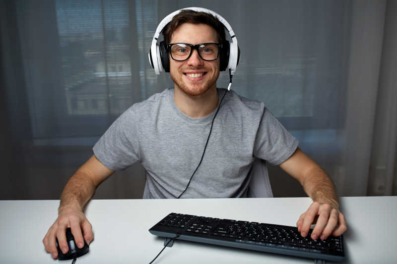 男人戴着耳机在家玩电脑