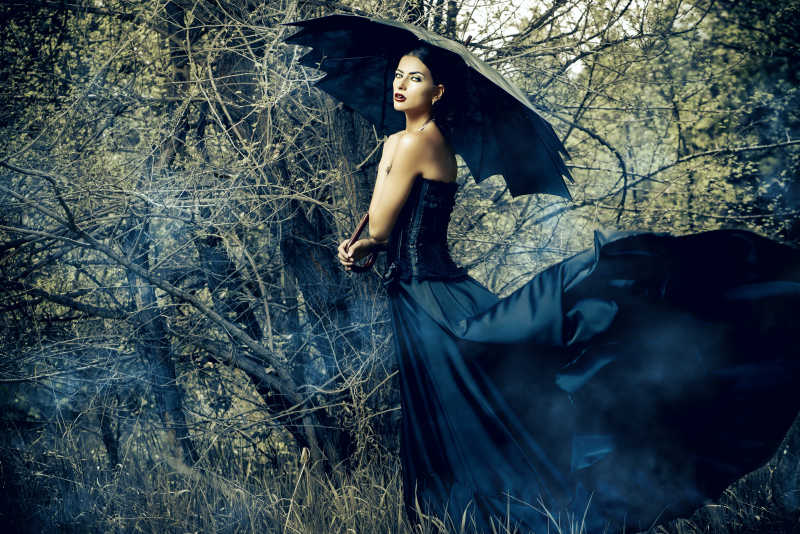 神秘森林的美丽女人穿着黑衣打着黑色的伞