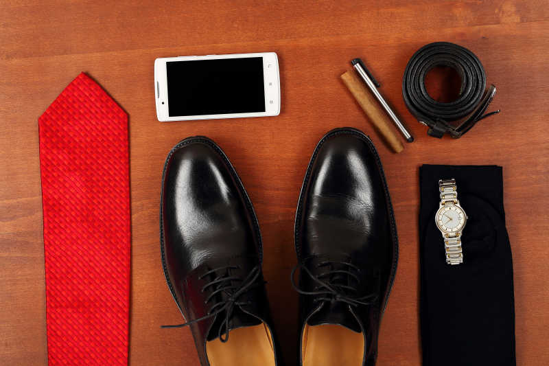 木板上的手机皮鞋领带雪茄皮带和手表