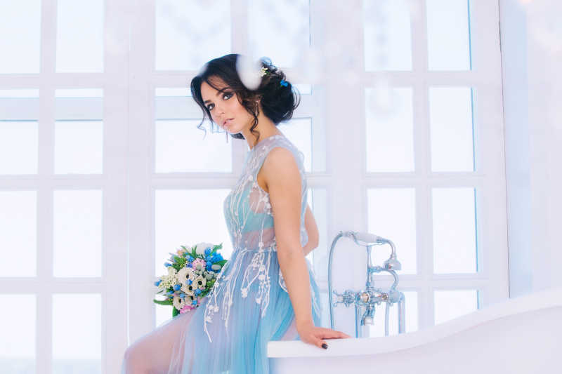坐在浴缸上的美丽蓝色纱裙新娘