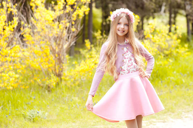时髦的小女孩穿着时髦的粉色衣服在户外摆姿势