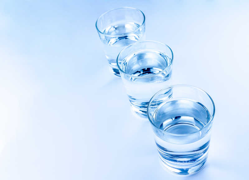 蓝色桌面上的玻璃水杯有三个