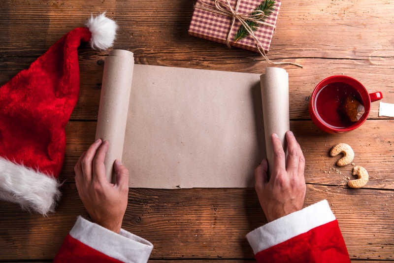 木桌上穿着圣诞衣服的老人拿着愿望清单