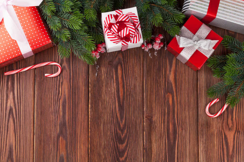 木纹理背景下的圣诞礼物盒拐杖糖和圣诞树枝