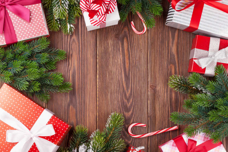 木纹理背景下的红色的礼物盒拐杖糖和圣诞树枝