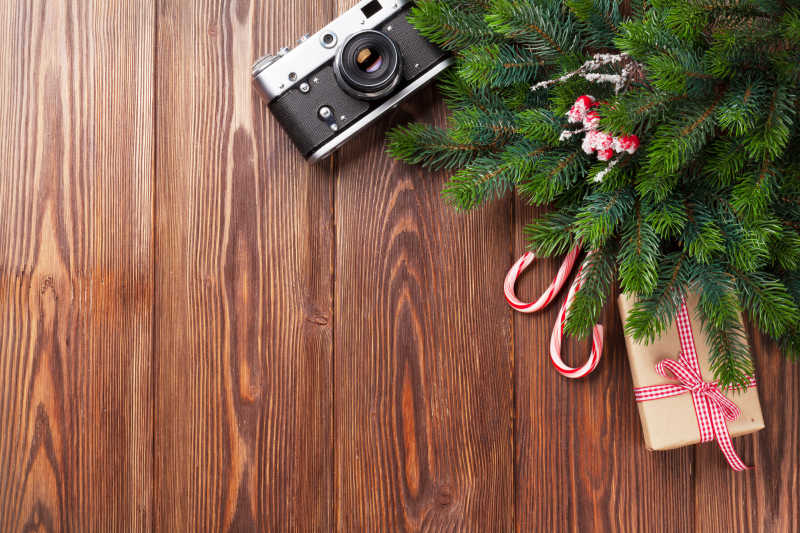 木纹理背景下的圣诞树枝礼物和相机