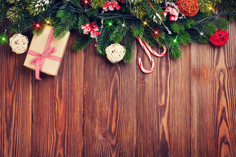 木纹理桌上的圣诞树树枝圣诞灯礼品盒和糖果棒