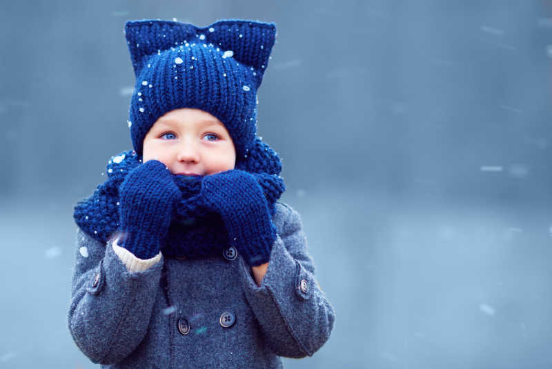 可爱的小男孩穿着冬衣的孩子在雪下行走