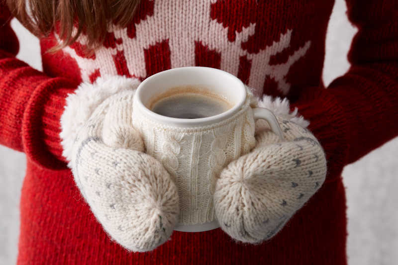 戴手套的女孩拿着冬天的热咖啡杯