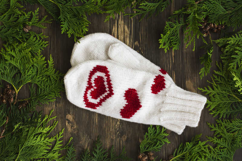 木制背景和雪松麸的暖白色针织手套