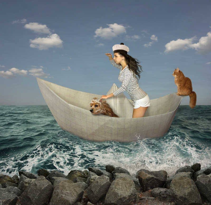 女孩和她的猫和狗在纸船上旅行