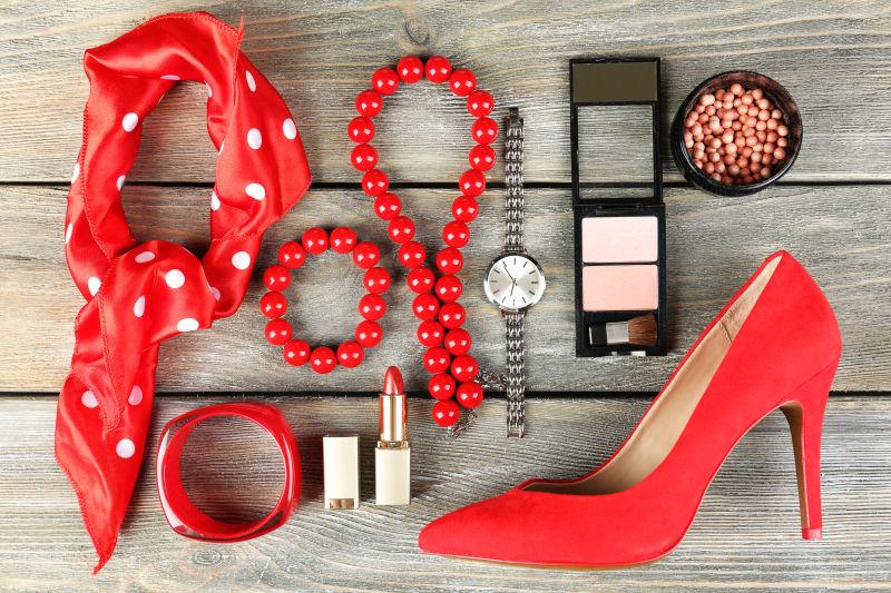 木桌上的红色服装配饰和化妆品