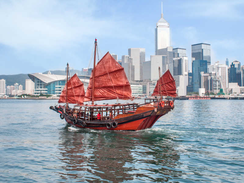 香港传统的红色帆垃圾船和城市大楼