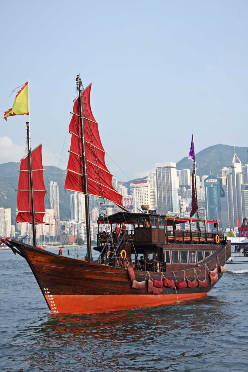 香港建筑大楼背景前的红色拉货帆船