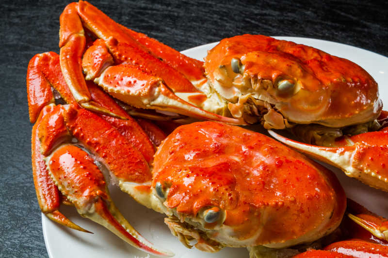 黑色桌上白色盘子里的红色的煮熟了的螃蟹