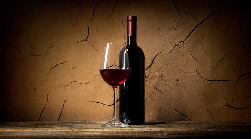 黏土背景下的葡萄酒杯和酒瓶