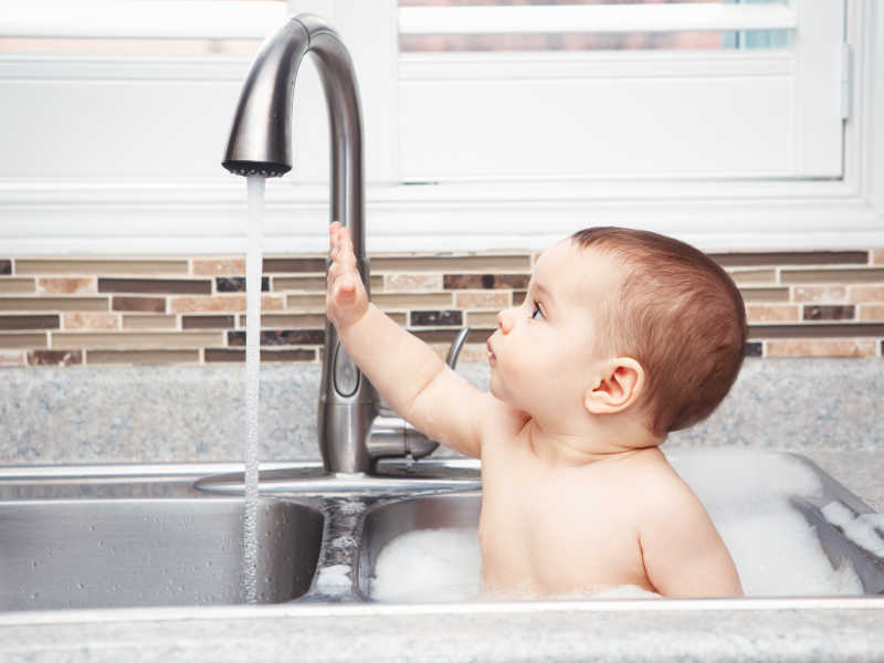 在洗碗池里玩水的小婴儿