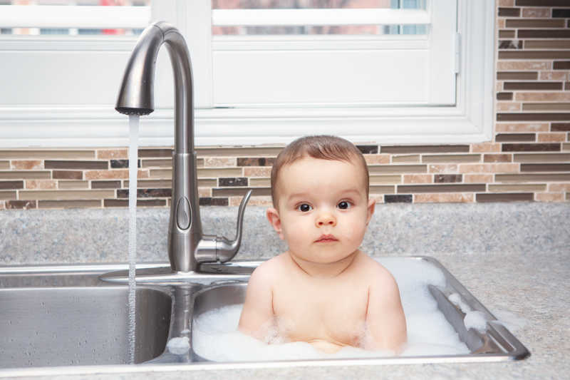 可爱的白人婴儿在洗碗池里
