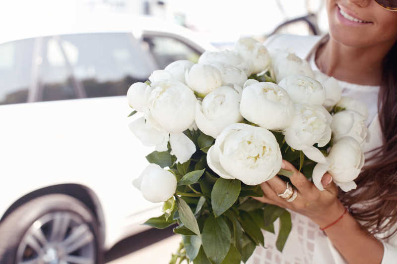 幸福的女人手里拿着美丽的白牡丹花束