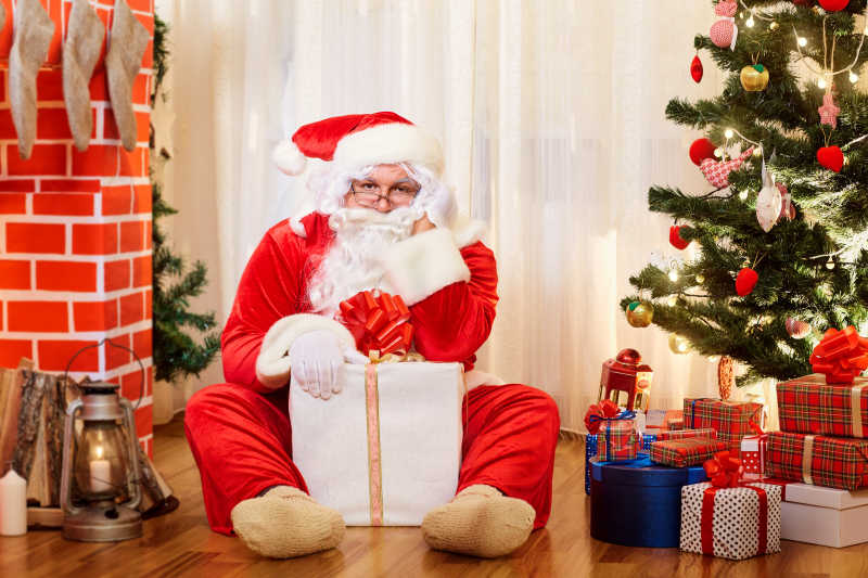 圣诞老人抱礼物坐在地上