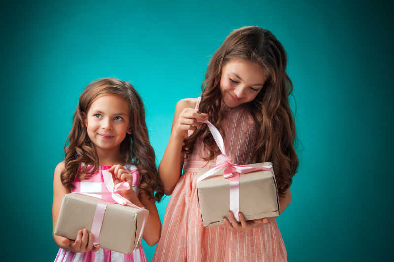 蓝色背景下拆开礼物的两个小女孩