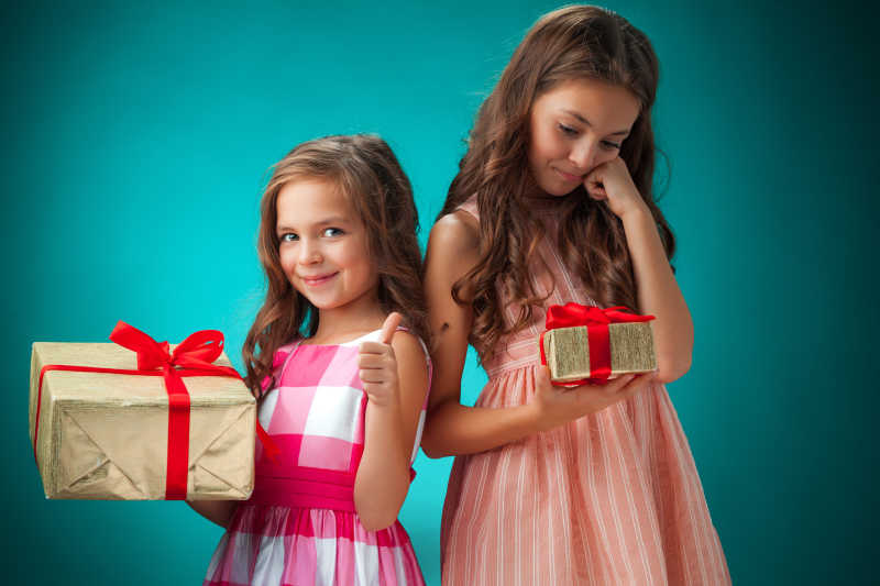 蓝绿色背景下包着礼物的可爱的小女孩