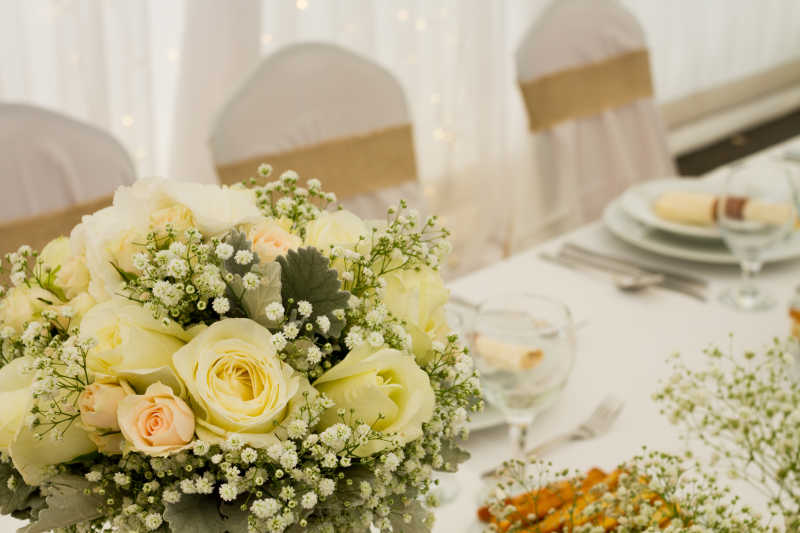白色背景下结婚餐桌上的餐具和黄色花朵装饰