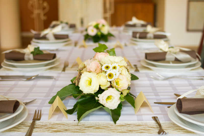 白色背景下结婚餐桌上的餐具和花朵装饰