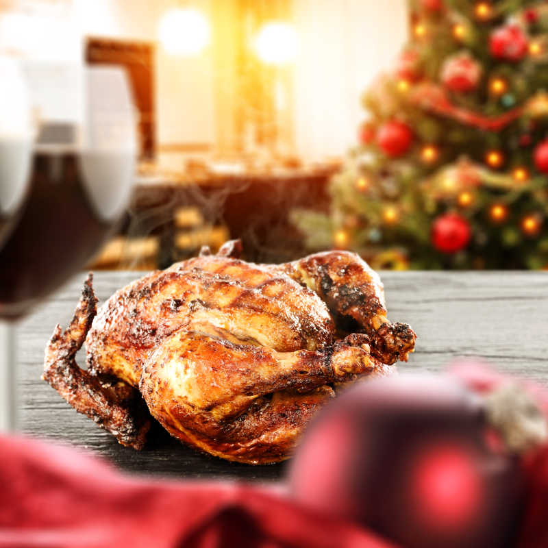 圣诞节背景下木桌子上的美味烤鸡