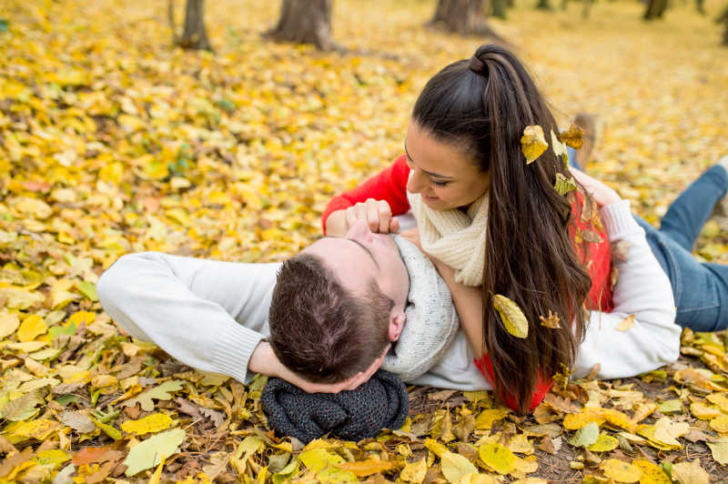 秋天公园里美丽的情侣躺在地上