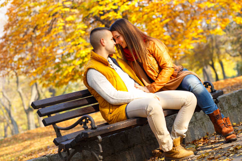 一对年轻夫妇坐在公园的长椅上