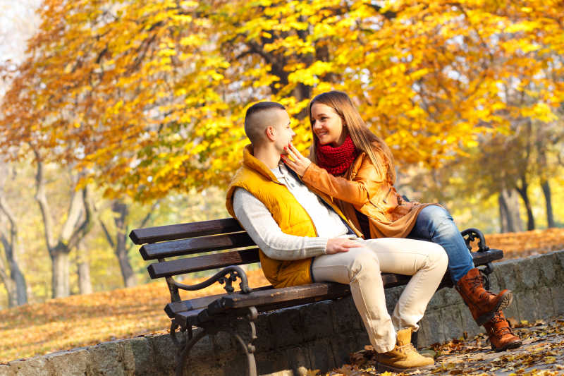 年轻的情侣在公园里的长椅上互相看着对方