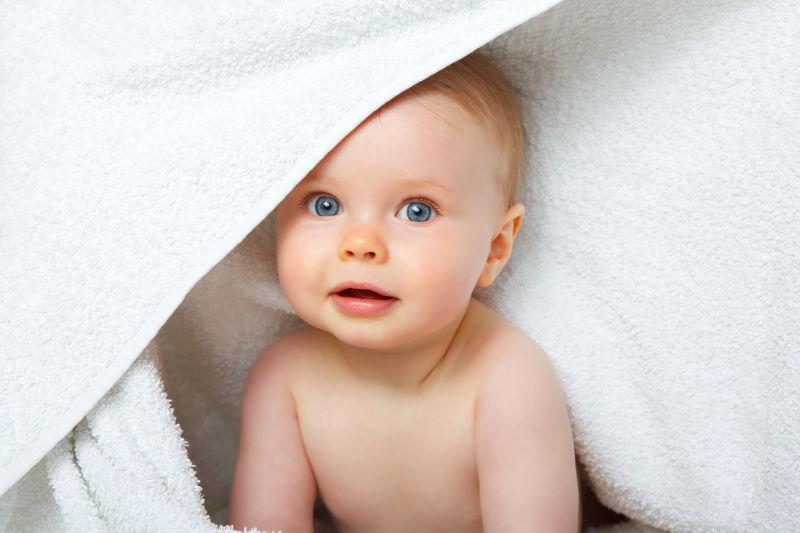 白色毛巾下微笑的婴儿