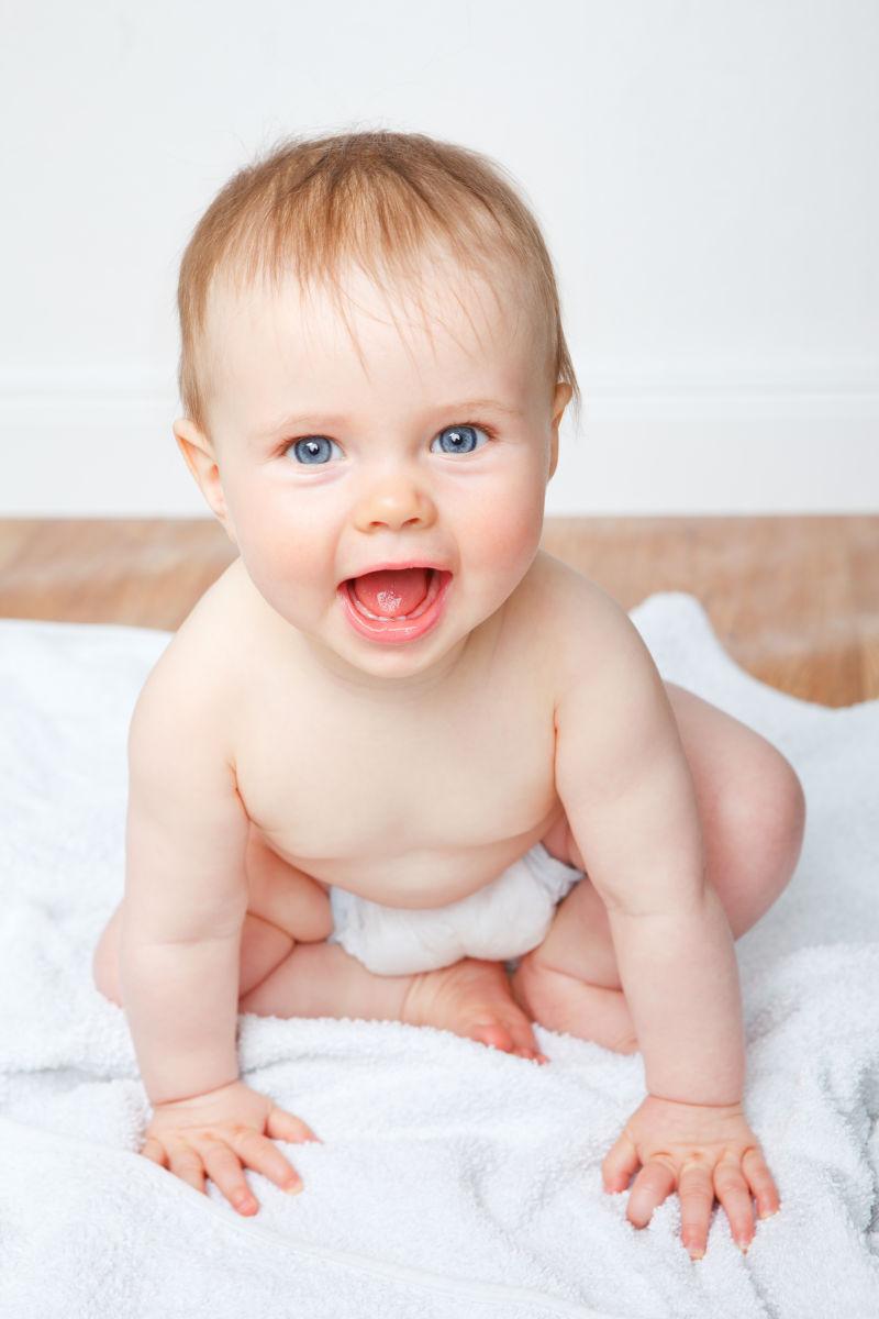 坐在白色浴巾上微笑的婴儿