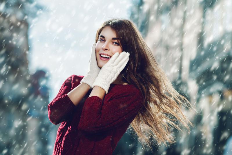 下雪背景下带着手套摸脸的美女